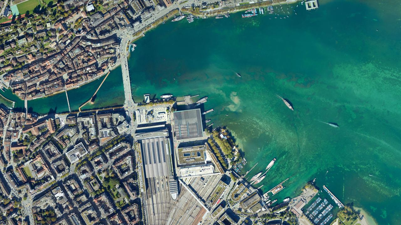 Orthofoto von Luzern senkrecht von oben, links die Altstadt und die Reuss mit der Kapellbrücke, in der Mitte Seebrücke, Kultur- und Kongresszentrum und Bahnhof mit Gleisfeld, rechts das Seebecken mit Kursschiffen