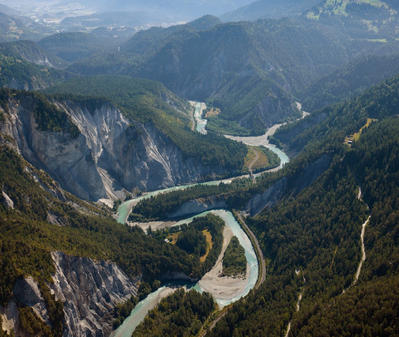 Luftaufnahme einer Schweizer Flussschlucht mit türkisfarbenem Wasser, Felswänden und Wald