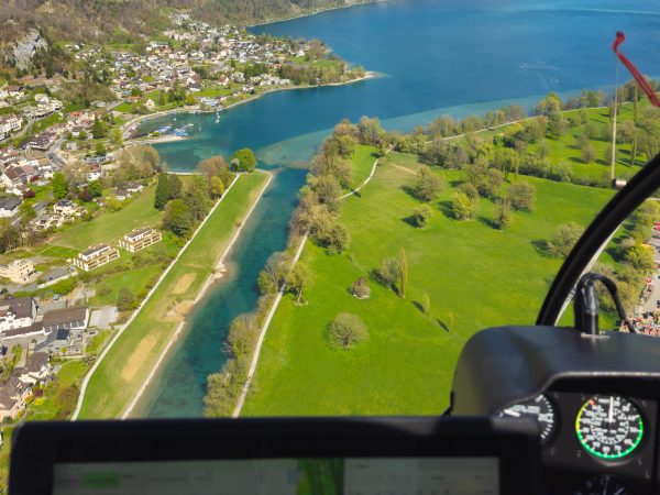 Blick aus dem Cockpit während einer Vermessungsbefliegung über See und Ortschaft