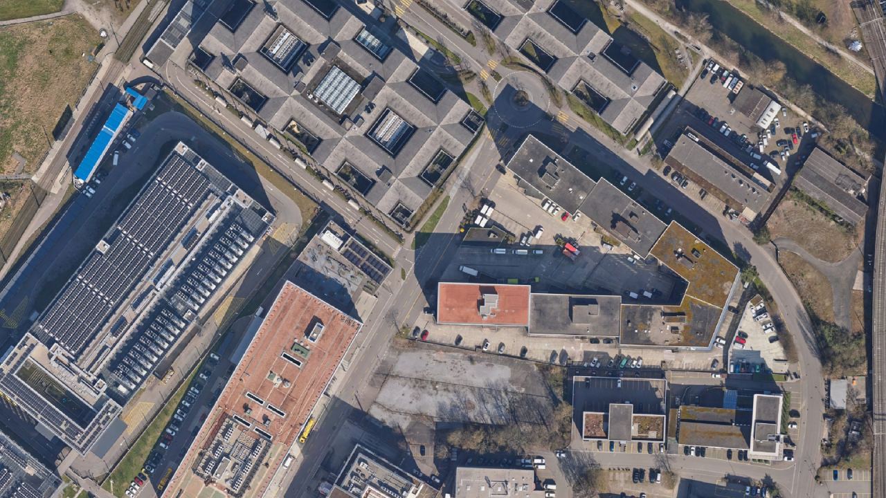 Orthofoto eines Gewerbegebiets in Opfikon mit Hallen, Solardächern und Bahnlinie