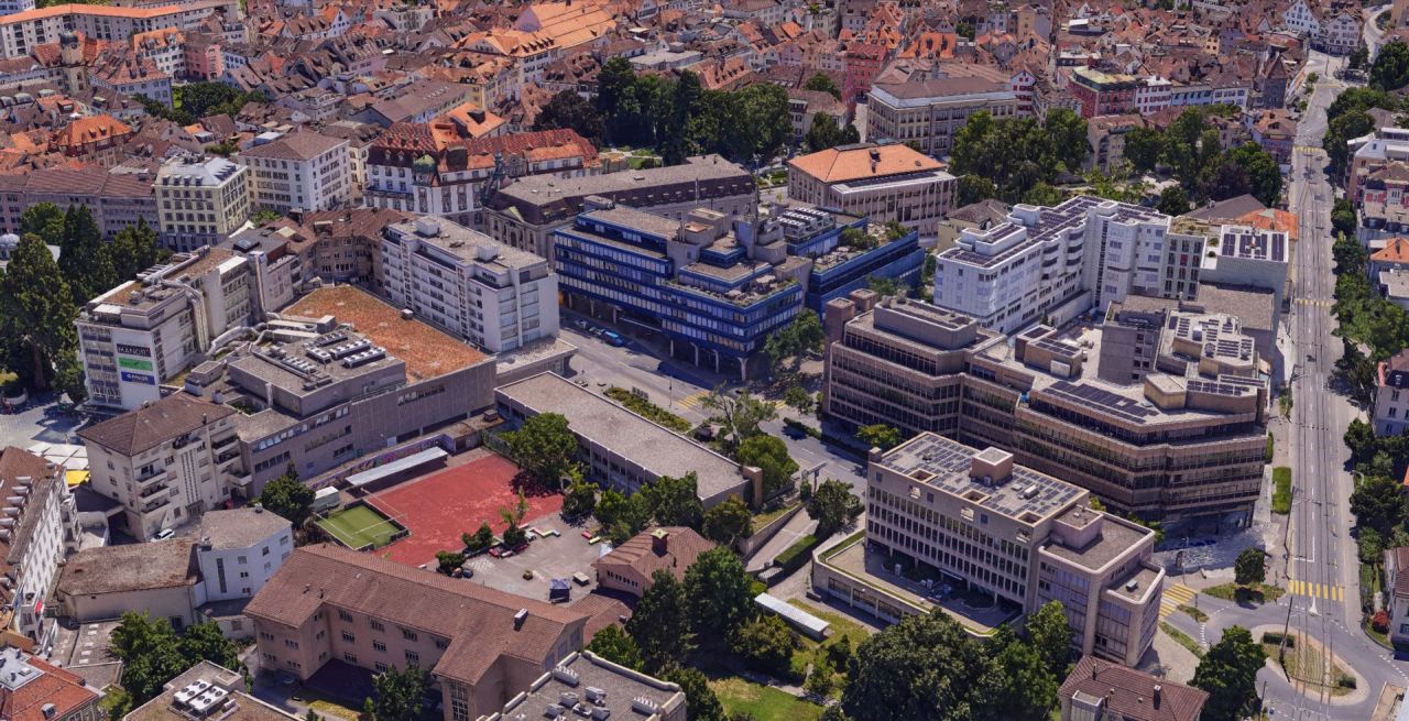 Texturiertes 3D-Mesh der Churer Innenstadt aus dem Schrägblick, Geschäftshäuser und ein Sportplatz im Vordergrund, dahinter die Altstadt